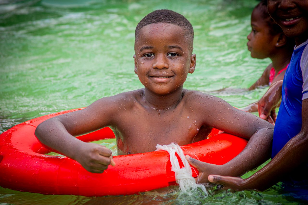 Smiling child with friends enjoying a summer swim with an inflatable ring.